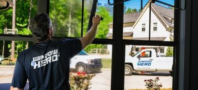 A Window Hero professional uses a squeegee to clean the inside of a home's window.