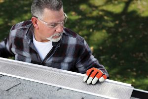 A man installing gutter guards on a residential property.