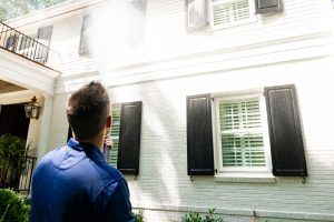 A Window Hero professional inspects a home's exterior.
