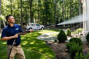 A Window Hero professional pressure washing a large home's exterior surfaces.