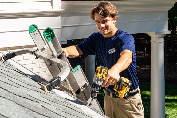 A Window Hero professional using a power drill to install a gutter guard.